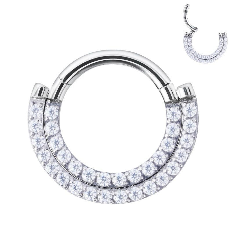 Clicker ring doppia fila cz stone trasparenti.Questo piercing realizzato in titanio ASTM F136 da implantologia certificato. E' dotato di cerniera, che rende la chiusura molto semplice: basta tirare il segmento per aprirlo, inserire il gioiello nel piercing e chiuderlo con un click. La parte frontale presenta una doppia fila con una serie di scintillanti pietre che ti faranno splendere.