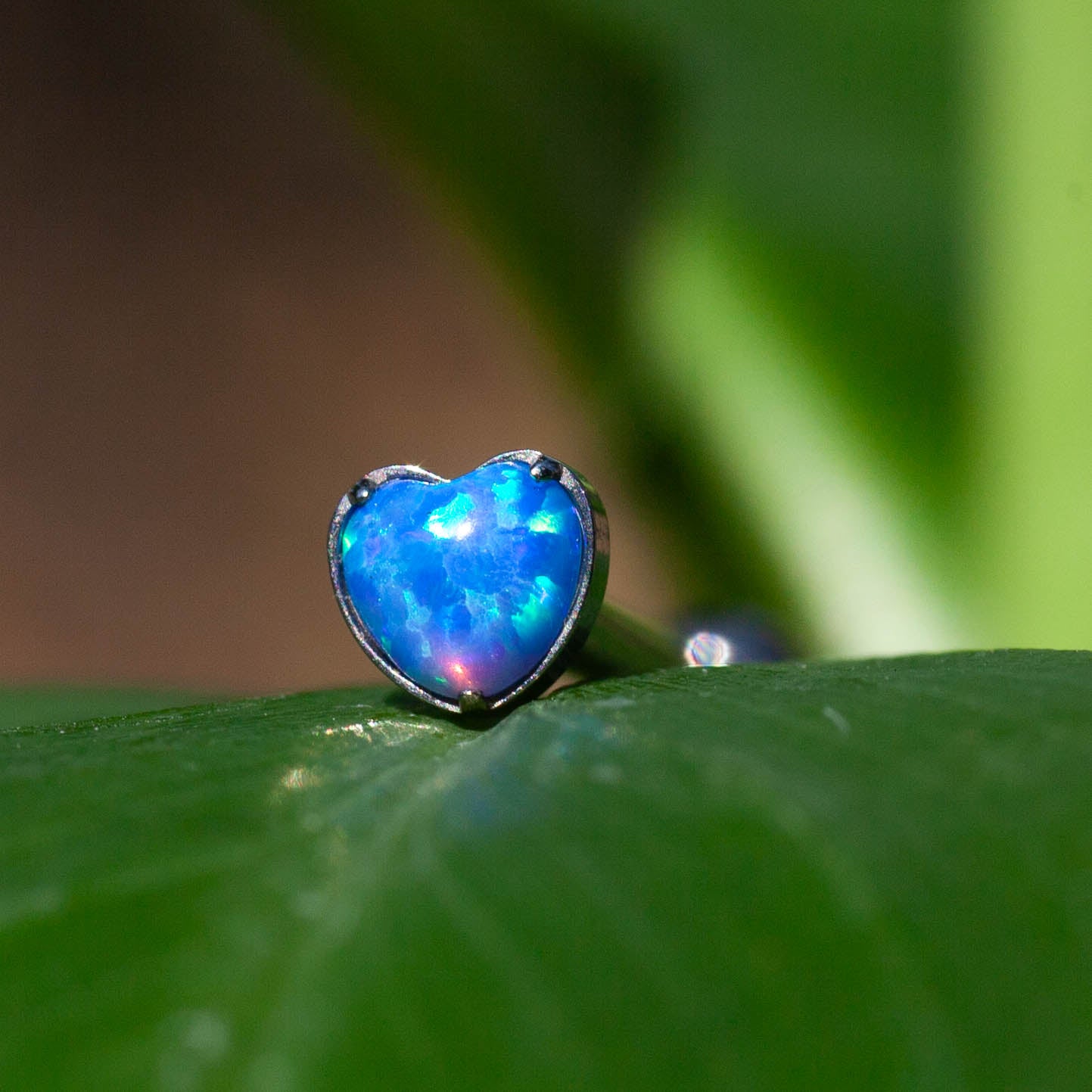 Cuore con opale sintetico, su base in titanio ASTM F136 da implantologia certificato. L'opale sintetico riproduce fedelmente i colori più vivaci e luminosi che esistono in natura. Si tratta di un colore puro che non sbiadisce col tempo. Come l'opale naturale, la struttura interna genera una diffrazione della luce, che porta ad un colore forte e lo rende davvero versatile. Consigliato per chi ama abbinamenti particolari.