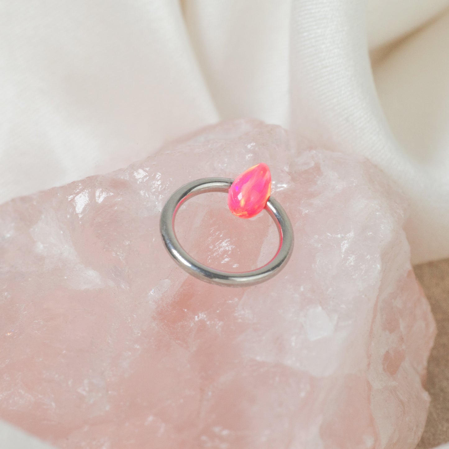 Ring in titanio ASTM F136 da implantologia certificato con opale. Questo scintillante ring realizzato in titanio nella parte frontale presenta uno splendido opale rosa "hot pink" che arricchisce il gioiello.